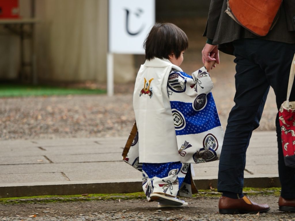 Un symbole d'un voyage sur mesure avec un enfant en kimono traditionnel tenant la main d’un adulte.